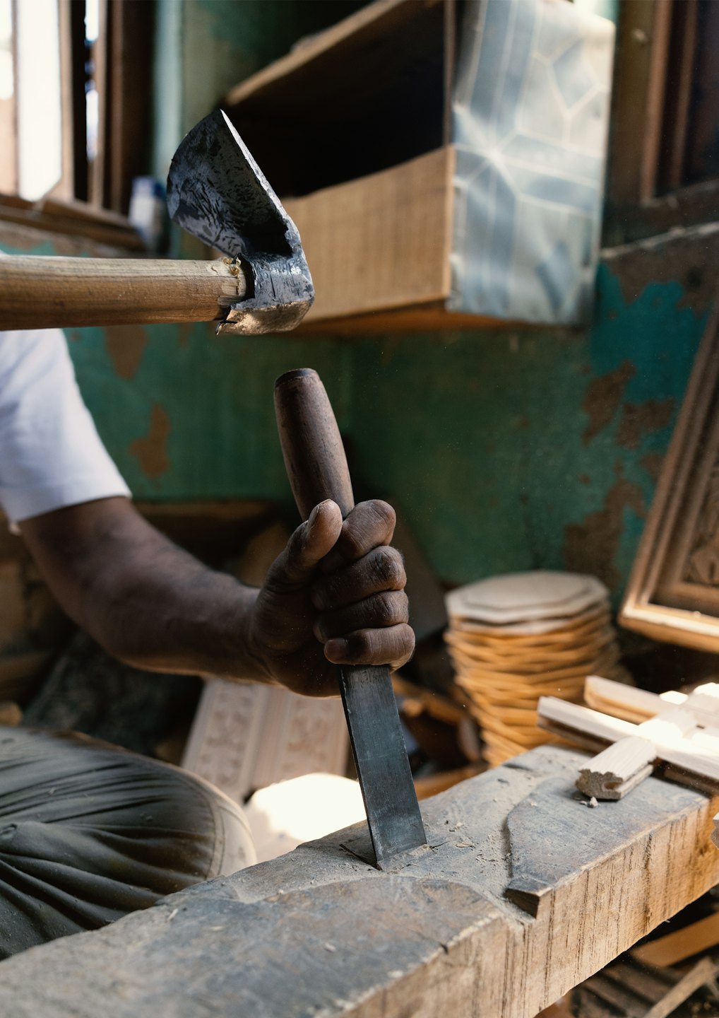 Mani che usano scalpello e mazzuolo per intagliare una trave di legno.